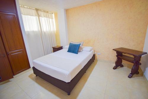 a bedroom with a bed and a wooden table at Hotel Toledo Plaza in Armenia