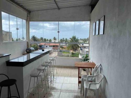 a kitchen with a bar with stools and a large window at Casa de Veraneio IOS in Ilhéus