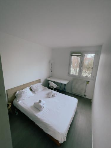 ein Schlafzimmer mit einem weißen Bett und Handtüchern darauf in der Unterkunft Appartement Proche U Arena et La Défense in Nanterre