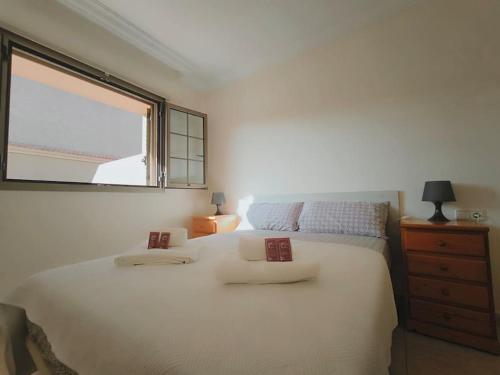 a bedroom with a large white bed with a window at Poris puesta de sol 2 in Santa Cruz de Tenerife