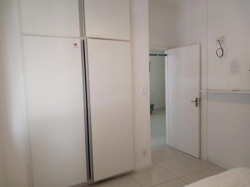 a room with white walls and sliding glass doors at Apartamento do Bruno - 1 quarto e sala predio vista ao mar- frente a praia do gonzaga in Santos