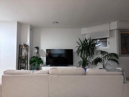 sala de estar con sofá blanco y TV de pantalla plana en Appartement 120m2 à Enghiens les bains, en Enghien-les-Bains