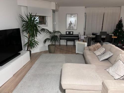 sala de estar con sofá blanco y TV en Appartement 120m2 à Enghiens les bains, en Enghien-les-Bains