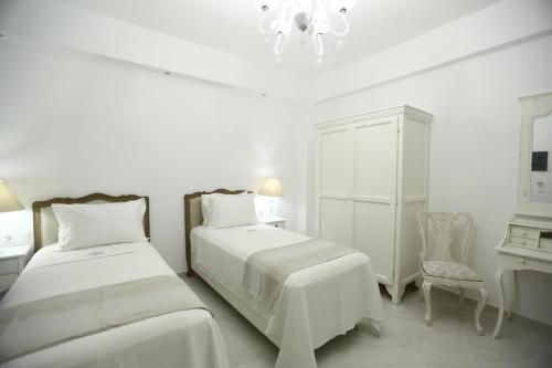 a hotel room with two beds and two lamps at The White Suites in Adamantas