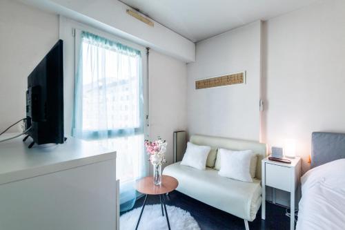 Cette chambre blanche dispose d'un canapé, d'une télévision et d'une fenêtre. dans l'établissement REVON - City center flat, à Annecy
