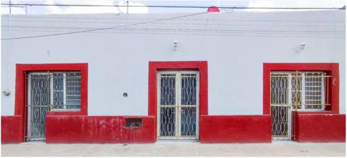 a red and white building with three doors at El canario in Mérida