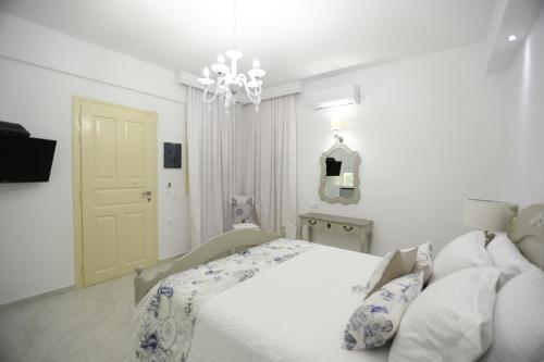 a white bedroom with a bed and a chandelier at The White Suites in Adamas