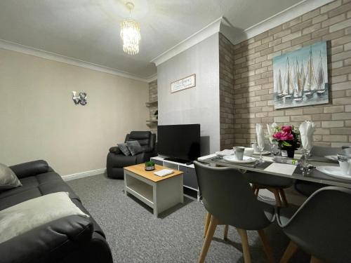 a living room with a couch and a table with chairs at Cosy home, family & contractor friendly 4 bedroom near Leeds centre, sleeps 7 in Leeds