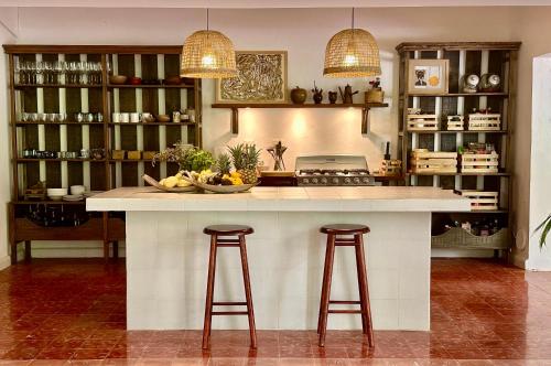 a kitchen with a large island with two bar stools at Casa Airam Beachfront Villa in Sian Kaan in Tulum