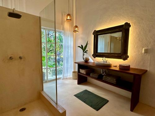 a bathroom with a mirror and a sink and a shower at Casa Airam Beachfront Villa in Sian Kaan in Tulum