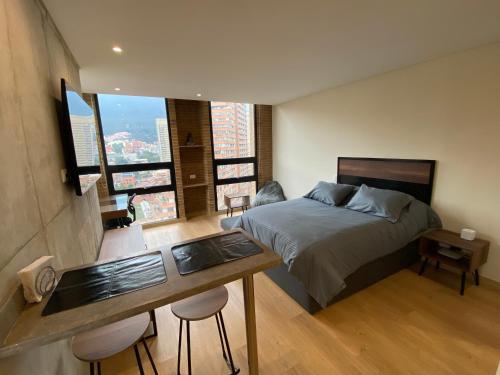 1 dormitorio con cama, escritorio y algunas ventanas en PENTHOUSE Centro Internacional Apartamento, en Bogotá