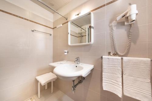 a white bathroom with a sink and a mirror at Hotel Niagara in Lignano Sabbiadoro