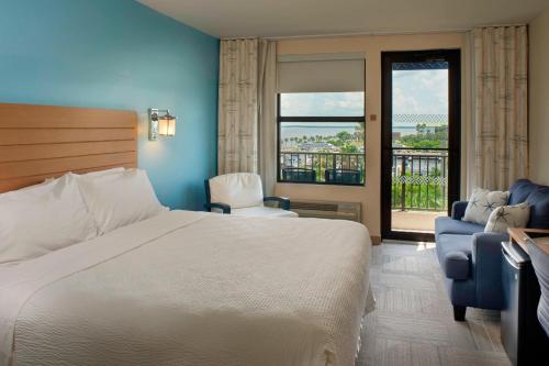 a hotel room with a bed and a balcony at Four Points by Sheraton Punta Gorda Harborside in Punta Gorda