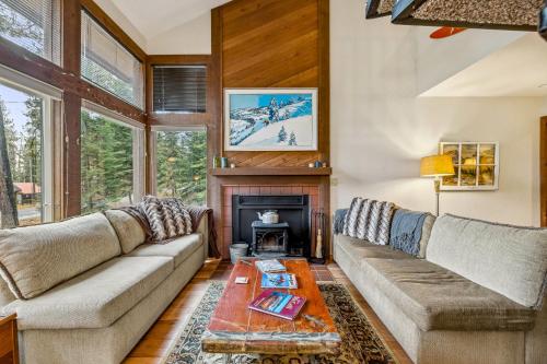 a living room with a couch and a fireplace at New! Brundage Meadows 1 - Bright, cozy - 2story - wood stove - forest views - by trails, lake, town in McCall