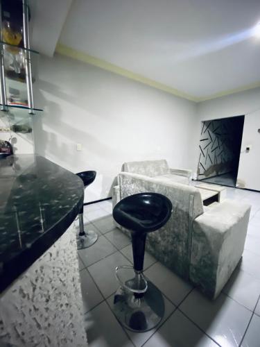 a room with a bar with a stool and a couch at Quarto disponível in Juazeiro do Norte