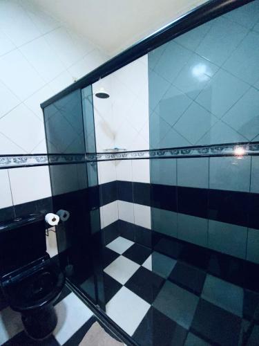 baño con aseo y suelo de baldosa blanco y negro. en Quarto disponível, en Juazeiro do Norte