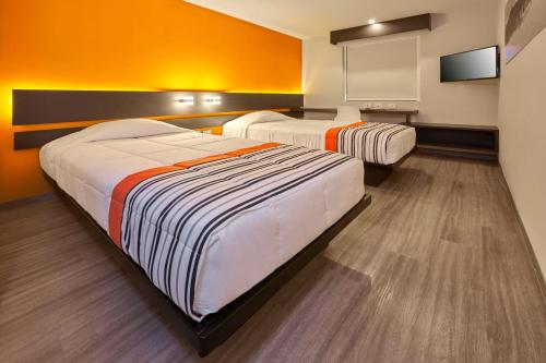 two beds in a room with orange walls at City Express Junior by Marriott Ciudad de México Sullivan in Mexico City