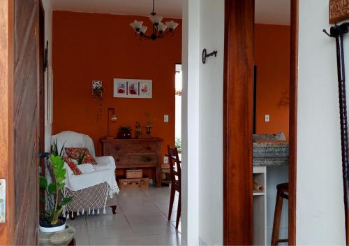 ペーニャにあるCasa de Praia Penha, Beto Carrero, 500m da Praia da Armaçãoのオレンジ色の壁のリビングルーム(白い椅子付)