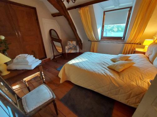 ein Schlafzimmer mit einem Bett, einem Fenster und einem Stuhl in der Unterkunft Gîte Ruillé-Froid-Fonds, 4 pièces, 6 personnes - FR-1-600-61 in Ruillé-Froid-Fonds