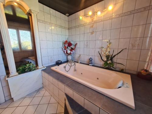 ein Badezimmer mit einer großen Badewanne mit Blumen in der Unterkunft Guestroom Anould, 1 pièce, 2 personnes - FR-1-589-510 in Anould