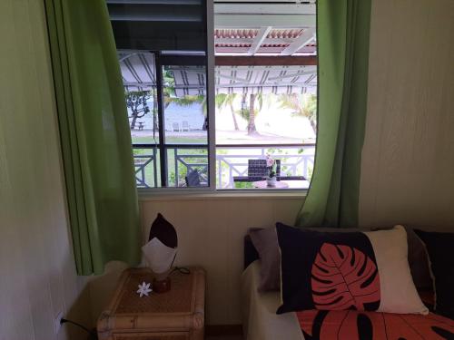 a bedroom with green curtains and a bed and a window at Fare Mama Rota - au bord de l'océan in Taputapuapea
