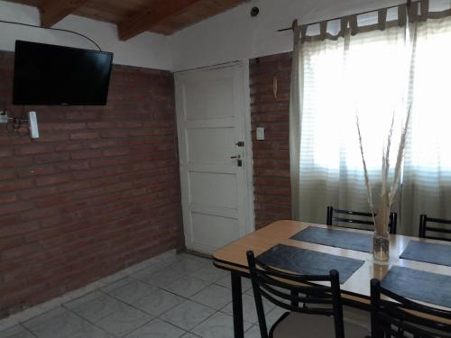 a dining room with a table and a television on a brick wall at El Pasaje in Malargüe