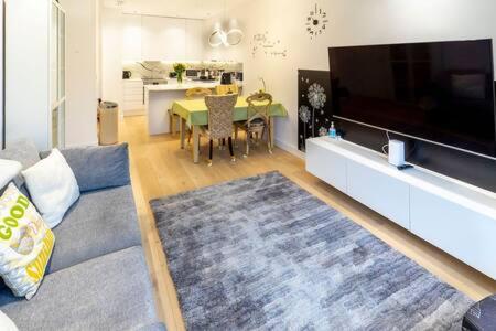 a living room with a couch and a large flat screen tv at Modern and Bright Ealing Common Duplex in London