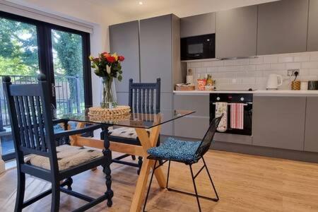 uma cozinha com uma mesa de vidro e 2 cadeiras em Beautiful Apartment Overlooking a Garden em Londres