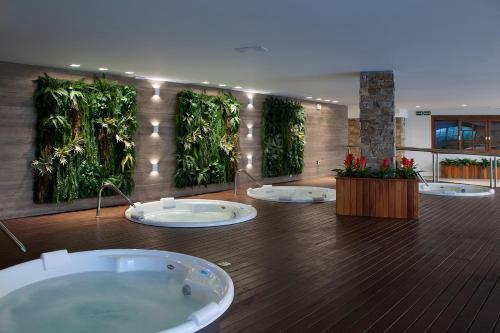 um quarto amplo com uma banheira com plantas na parede em Gramado Parks em Gramado