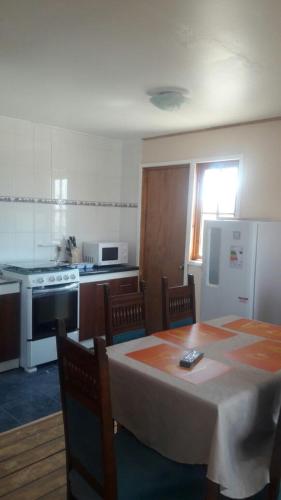 a kitchen with a table and chairs and a kitchen with a table and a refrigerator at Cabañas Miraflores ubicadas en zona central de punta de choros a una cuadra de la playa de punta de choros in Choros