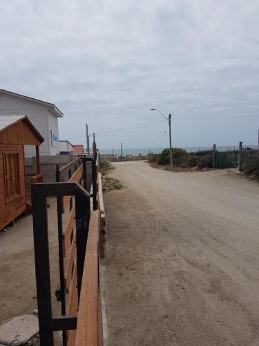 een onverharde weg met een hek naast een gebouw bij Cabañas Miraflores ubicadas en zona central de punta de choros a una cuadra de la playa de punta de choros in Choros