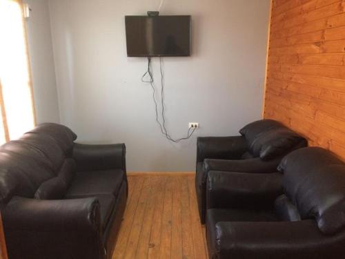 sala de estar con 2 sofás de cuero y TV en Cabañas Miraflores ubicadas en zona central de punta de choros a una cuadra de la playa de punta de choros, en Choros