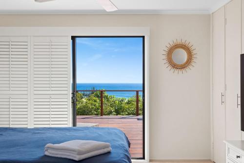a bedroom with a bed and a view of the ocean at 11 Warbler Crescent in Kianga