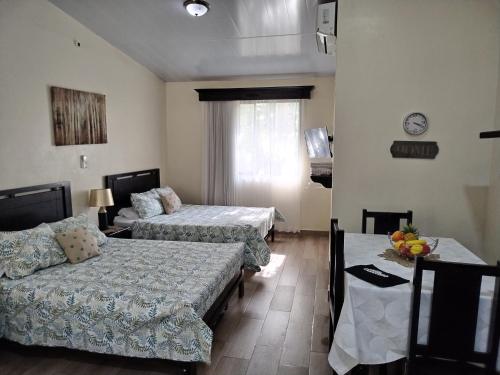 a room with two beds and a table with a couch at Villa jr 4 by Villas Oasis Guacalillo in Tárcoles
