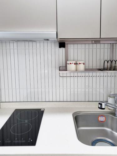 a kitchen with a sink and a white tiled wall at Sokcho Summitbay 1705 "Panoramic Ocean View" in Sokcho