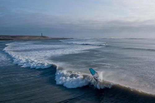 a wave in the ocean with a surfboard in the water at La Arteza Pacasmayo in Pacasmayo