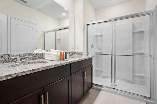 La salle de bains est pourvue de 2 lavabos et d'une douche en verre. dans l'établissement 6 Bedroom 6 Bathroom Solterra 7623 Ol, à Davenport