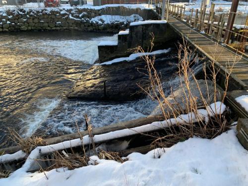 a bridge over a river with snow on the ground at The Mill House - Saeby Watermill in Sæby