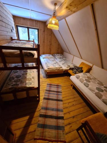 a attic room with three bunk beds and a rug at Chata pri Veľkej Rači in Oščadnica