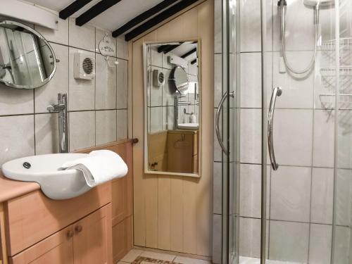 een badkamer met een wastafel en een douche bij Smugglers Cottage in New Milton