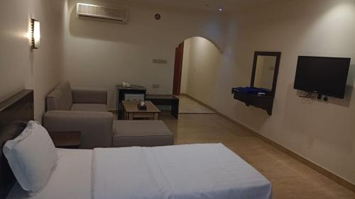 Habitación con cama, TV y sofá. en فندق سفير العرب, en Rafha