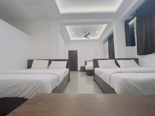 a row of beds in a room with a ceiling at AROMA INN in Kalpetta