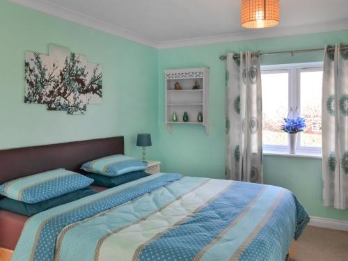 Un dormitorio con una cama con paredes azules y una ventana en Pondside, en Boston