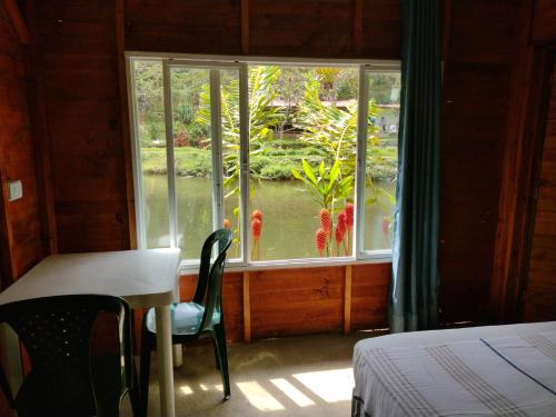 a bedroom with a table and a window with a view of a pond at sapiens house cabaña del lago premium in Cali