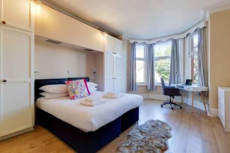 1 dormitorio con 1 cama grande, escritorio y ventanas en Spacious Apartment In The Heart Of Ealing Broadway en Londres