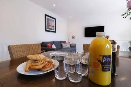 einen Tisch mit einer Flasche Orangensaft und ein paar Gläsern in der Unterkunft Ealing Common Apartment with Balcony in London