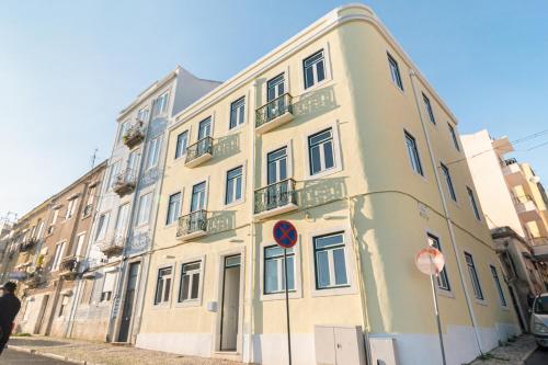 un grand bâtiment jaune avec balcon dans une rue dans l'établissement Arroios Concept Apartments by Homing, à Lisbonne