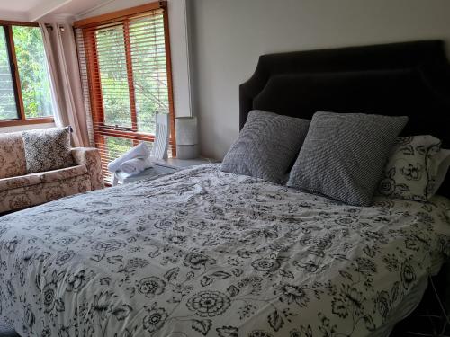 a bed with a black and white comforter and pillows at Lark Cottage in Burrawang