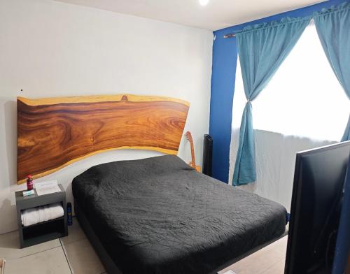 1 dormitorio con 1 cama con cabecero de madera y ventana en "Paco's Depa" Habitación privada en Depa compartido en el Centro Histórico con alberca y gimnasio!, en Guadalajara