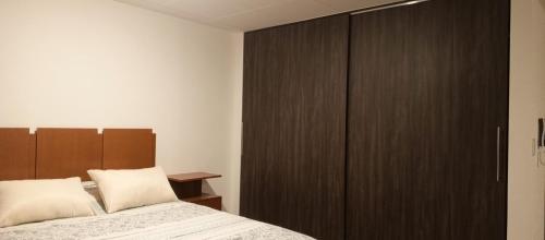 Monoambiente acogedor, cómodo e iluminado في لاباز: غرفة نوم مع خزانة خشبية كبيرة وسرير